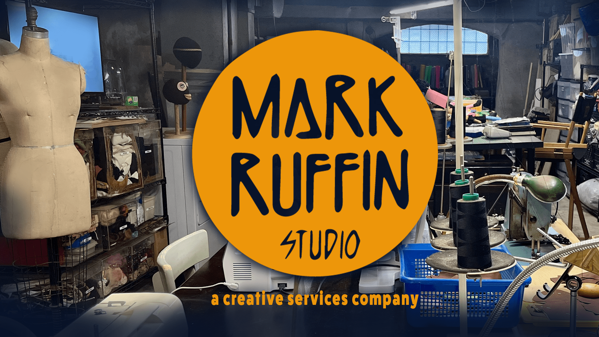 "Image of Mark Ruffin Studio: A creative services company specializing in the design and fabrication of costumes, puppets, dolls, and props. The studio is depicted as a vibrant workspace with artists working on various projects, surrounded by materials and tools for crafting costumes, puppets, dolls, and props."